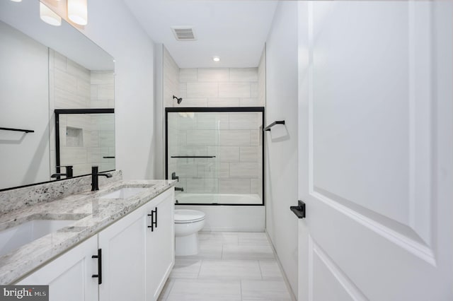 full bathroom with visible vents, double vanity, toilet, shower / bath combination with glass door, and a sink