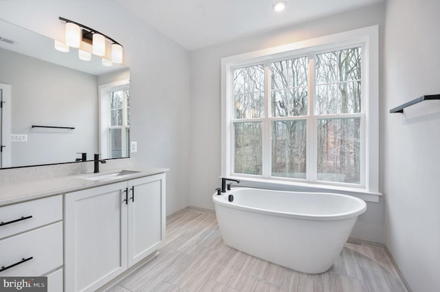 bathroom featuring vanity, visible vents, baseboards, recessed lighting, and a freestanding bath