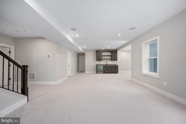 unfurnished living room with visible vents, baseboards, stairs, and light colored carpet