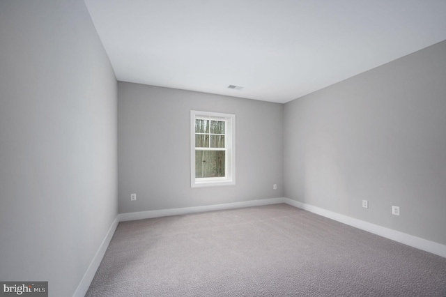 empty room with baseboards, visible vents, and light carpet