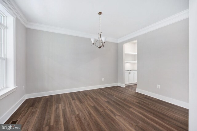 empty room with dark wood-style floors, an inviting chandelier, and ornamental molding