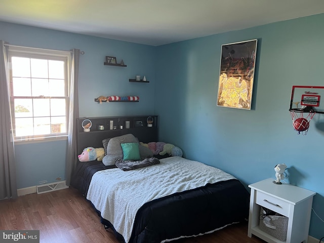 bedroom featuring baseboards, wood finished floors, and visible vents