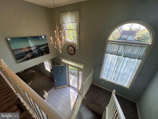 entrance foyer with baseboards, a chandelier, and carpet