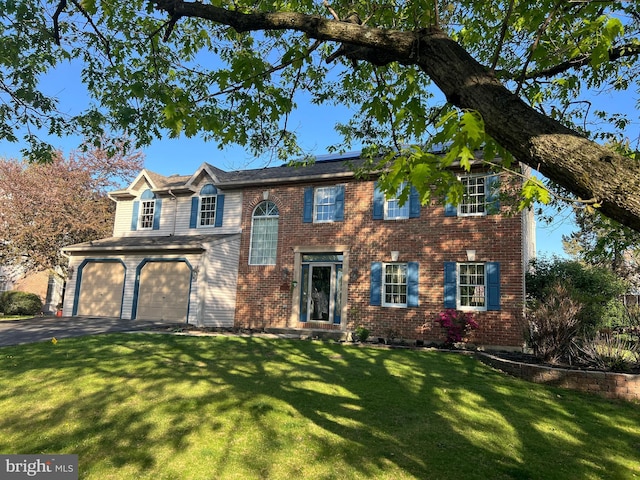 view of front of property featuring brick siding, a garage, driveway, and a front lawn