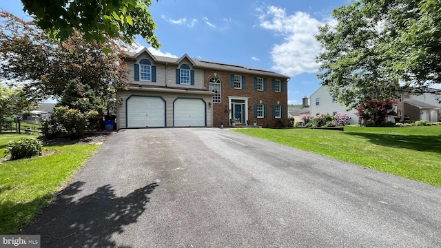 421 Coronet Dr, Blandon, PA 19510 - view of front of property featuring asphalt driveway, a front yard, an attached garage, brick siding, and roof mounted solar panels