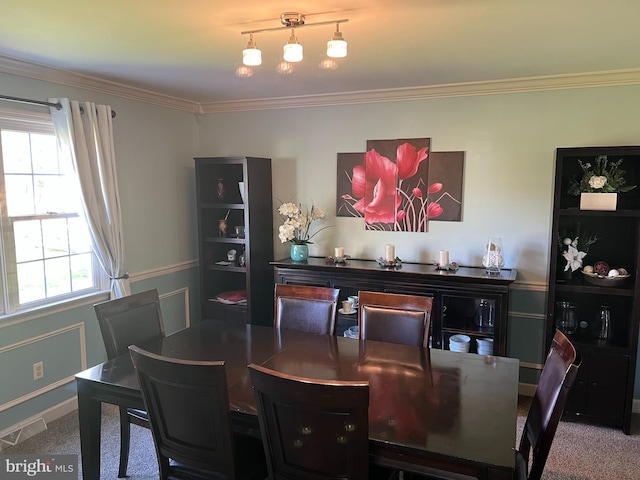 carpeted dining space with crown molding, baseboards, and visible vents