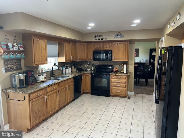 kitchen featuring decorative backsplash, light stone countertops, a sink, light tile patterned floors, and black appliances
