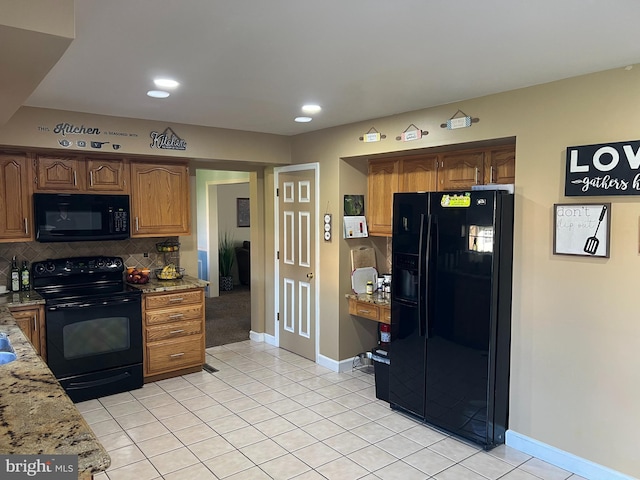 kitchen with light tile patterned floors, light stone counters, backsplash, and black appliances