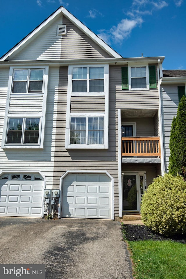 multi unit property with a balcony, driveway, and an attached garage