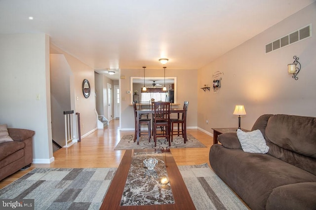 living room with baseboards, visible vents, and light wood-type flooring