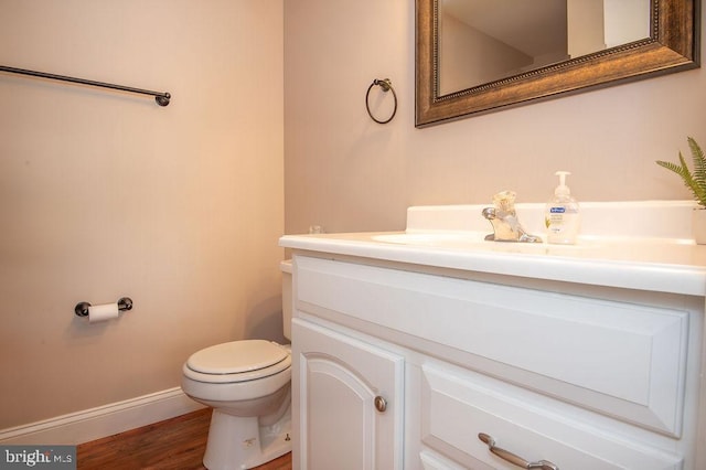 bathroom with baseboards, wood finished floors, toilet, and vanity