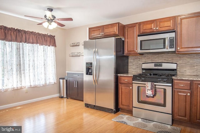 kitchen featuring backsplash, ceiling fan, appliances with stainless steel finishes, and brown cabinetry