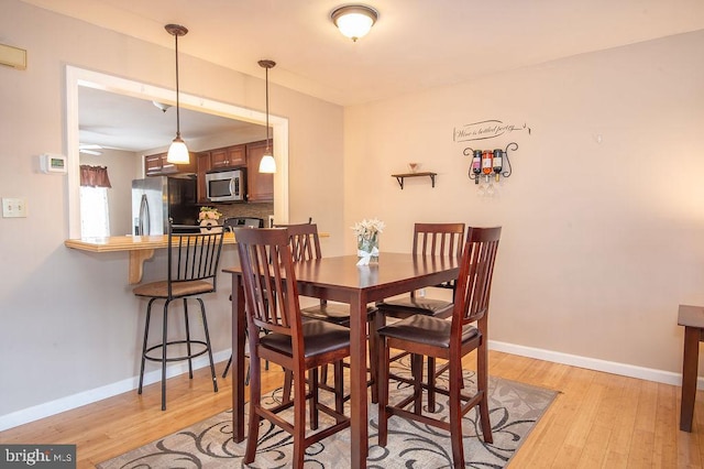 dining area with baseboards, light wood-type flooring, and a ceiling fan