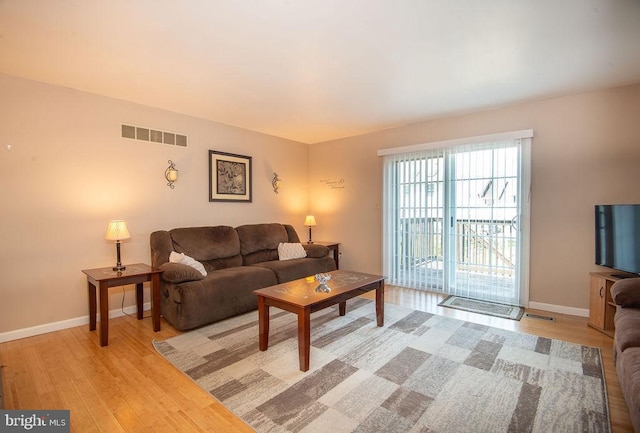 living area featuring baseboards, visible vents, and light wood finished floors