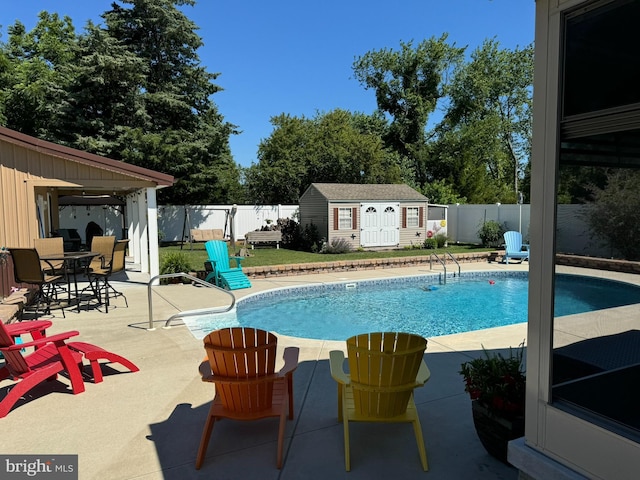 view of swimming pool featuring a patio, a fenced backyard, an outbuilding, and a fenced in pool