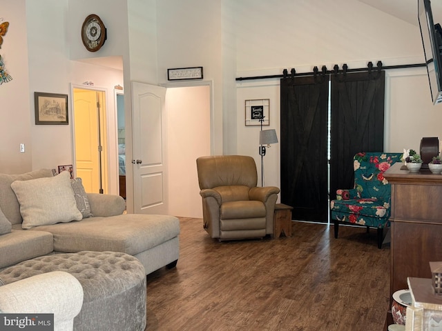 living area with a barn door, dark wood finished floors, and high vaulted ceiling