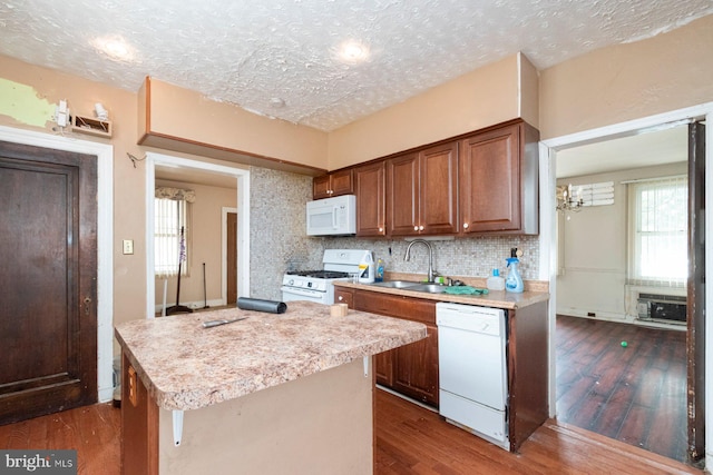 kitchen with a sink, white appliances, a wealth of natural light, light countertops, and dark wood finished floors