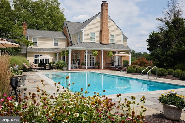 outdoor pool with french doors and a patio area