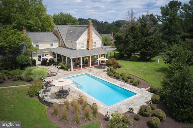 view of pool with fence, a patio area, a pool with connected hot tub, and a lawn