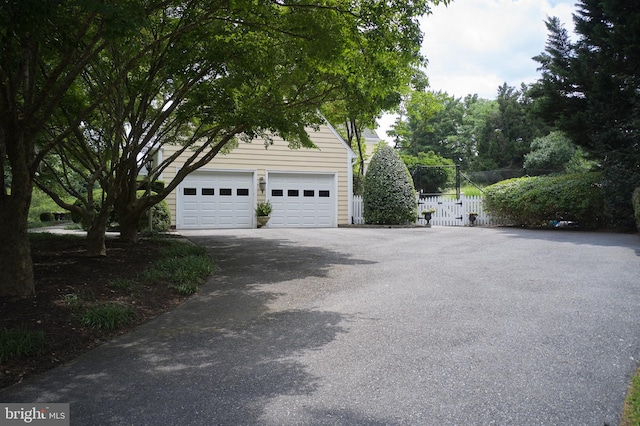 garage featuring driveway, fence, and a gate