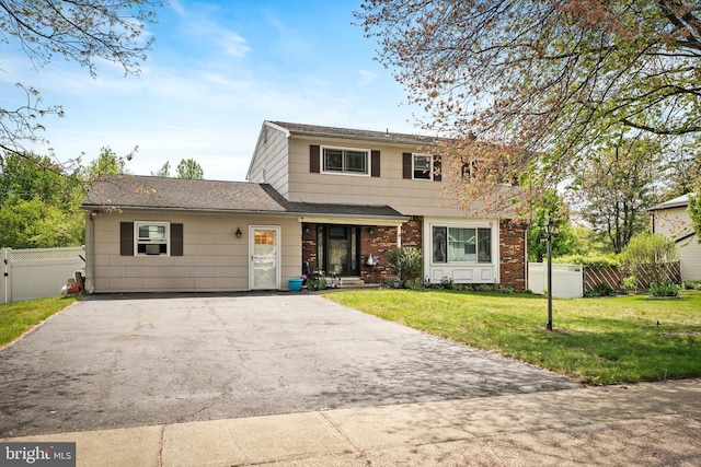 view of front of house with a shingled roof, a front lawn, fence, and driveway