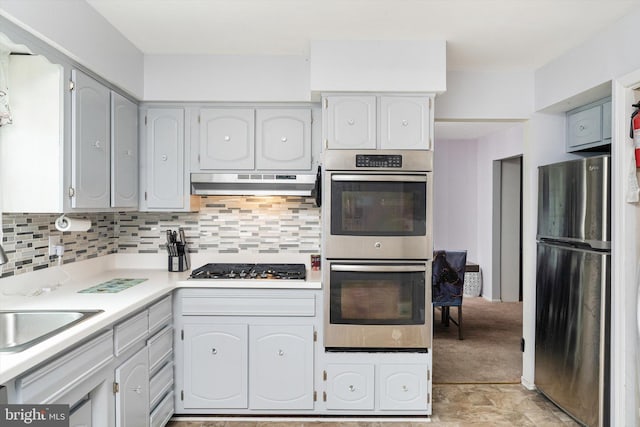 kitchen featuring a sink, light countertops, stainless steel appliances, backsplash, and under cabinet range hood