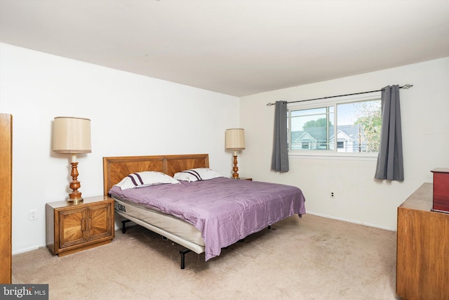bedroom with baseboards and light carpet