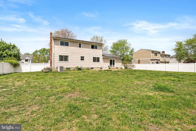 rear view of property with a yard, a chimney, and a fenced backyard