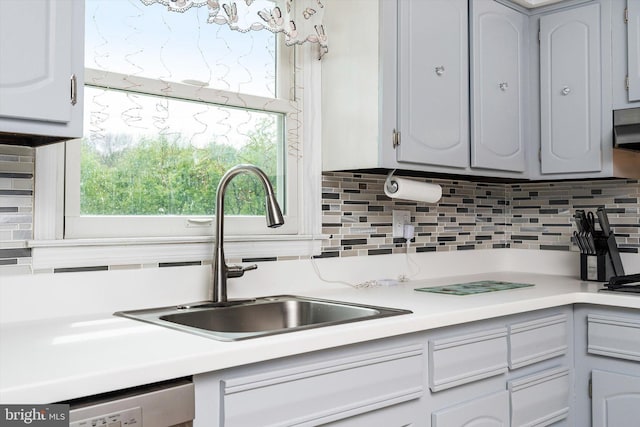 kitchen with light countertops, dishwasher, a sink, and tasteful backsplash
