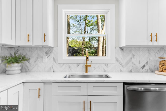 kitchen with stainless steel dishwasher, white cabinets, light stone countertops, and a sink