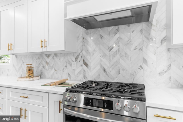 kitchen featuring stainless steel gas range, white cabinetry, wall chimney exhaust hood, and tasteful backsplash
