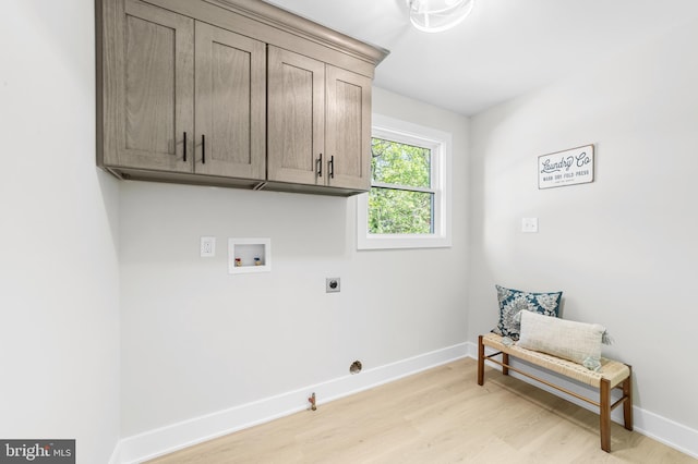 laundry room featuring electric dryer hookup, hookup for a gas dryer, light wood-type flooring, cabinet space, and baseboards