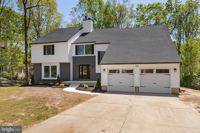 view of front facade with an attached garage, a shingled roof, a front yard, a chimney, and driveway