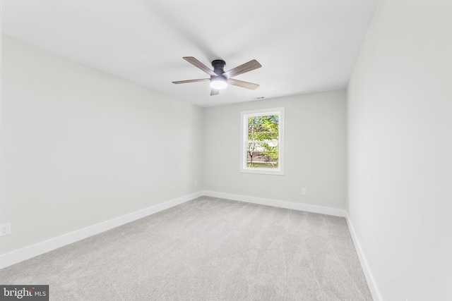 spare room with baseboards, a ceiling fan, and light colored carpet