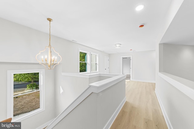 hallway with an upstairs landing, baseboards, a notable chandelier, light wood-style floors, and recessed lighting