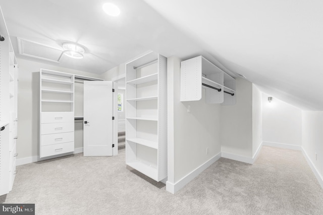 spacious closet with light colored carpet and attic access