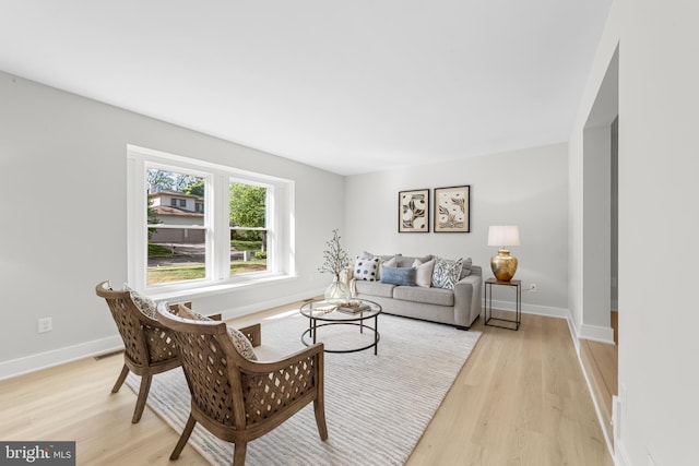 living room featuring light wood-type flooring, baseboards, and visible vents