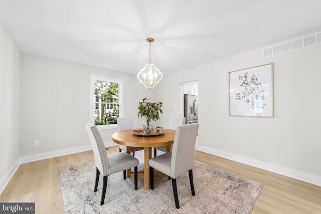 dining space featuring visible vents, baseboards, a chandelier, and light wood-type flooring