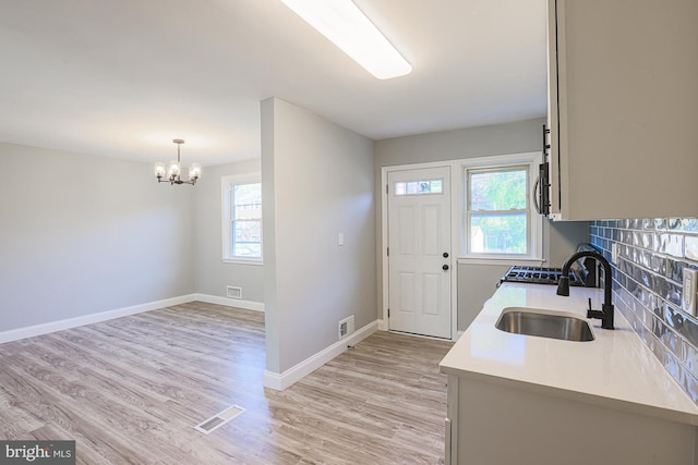 kitchen featuring a sink, light countertops, a chandelier, stainless steel microwave, and visible vents