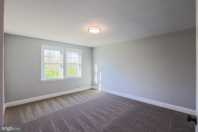 carpeted spare room featuring baseboards and visible vents