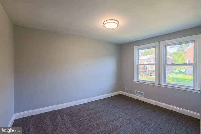 unfurnished room with visible vents, baseboards, and dark carpet