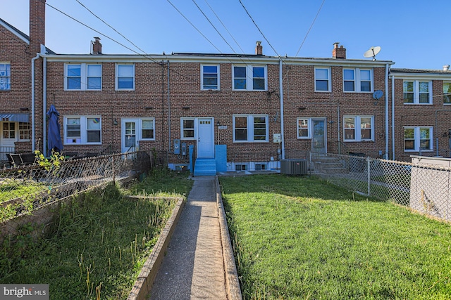 back of property with fence, a chimney, a lawn, and brick siding