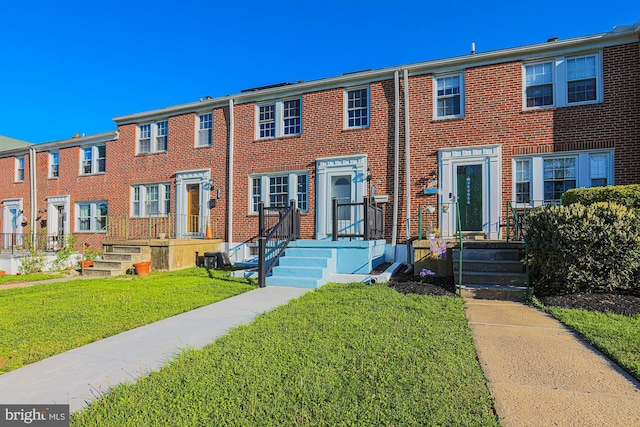 view of property featuring brick siding and a front lawn