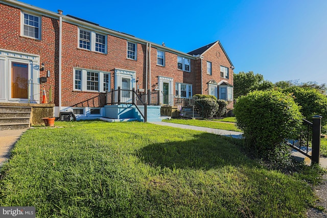 rear view of house featuring brick siding and a yard
