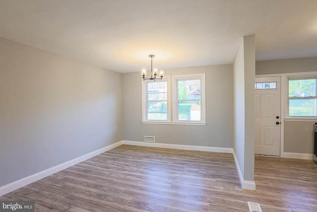 interior space with baseboards, visible vents, wood finished floors, and a notable chandelier