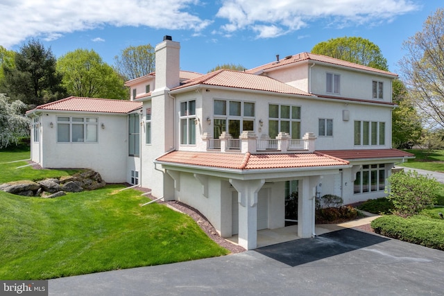 23 Deerfield Rd, Lancaster, PA 17603 - rear view of property with a balcony, a lawn, a tiled roof, a chimney, and stucco siding