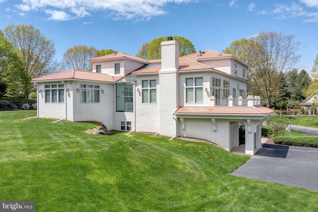 23 Deerfield Rd, Lancaster, PA 17603 - back of property featuring a chimney, stucco siding, a tile roof, a balcony, and a lawn