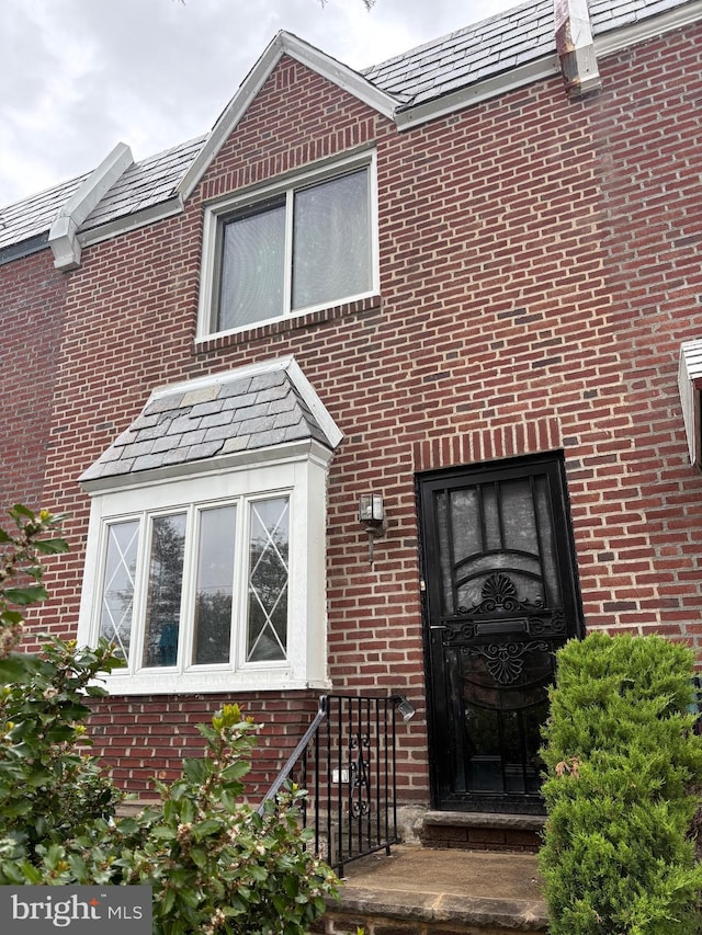 property entrance with a high end roof and brick siding