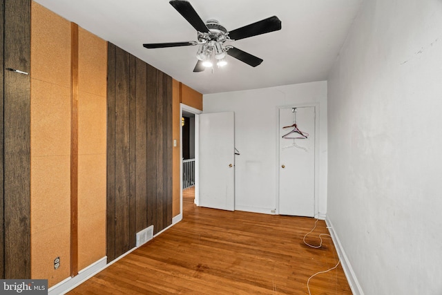 unfurnished bedroom featuring baseboards, ceiling fan, visible vents, and wood finished floors