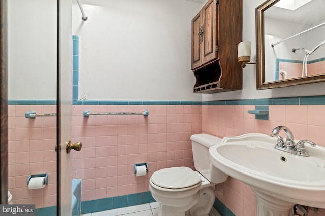 bathroom with a sink, tile walls, and walk in shower
